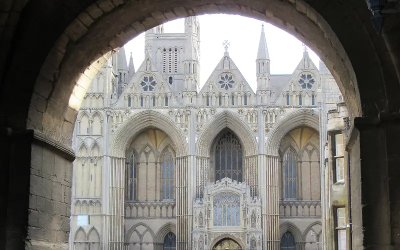 The west front of Peterborough Cathedral, seen through a stone archway